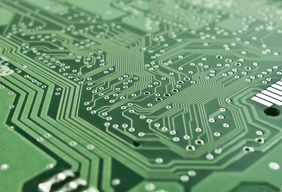 Macro view of a green printed circuit board with copper traces and solder pads.