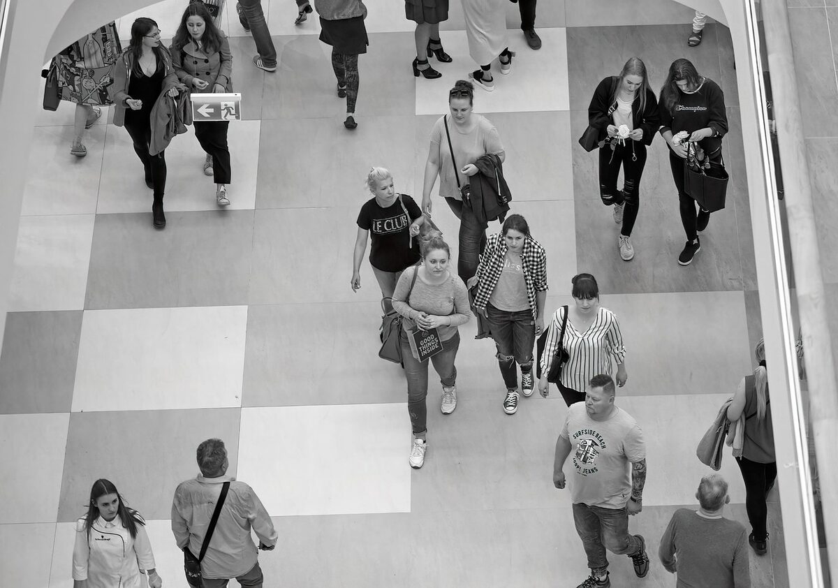 Overhead view of people in a mall concourse. Radar tracks each person's path; two individuals are flagged with a critically high heart rate.